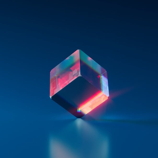 A multi-colored cube standing one of its edges with a slight reflection underneath it